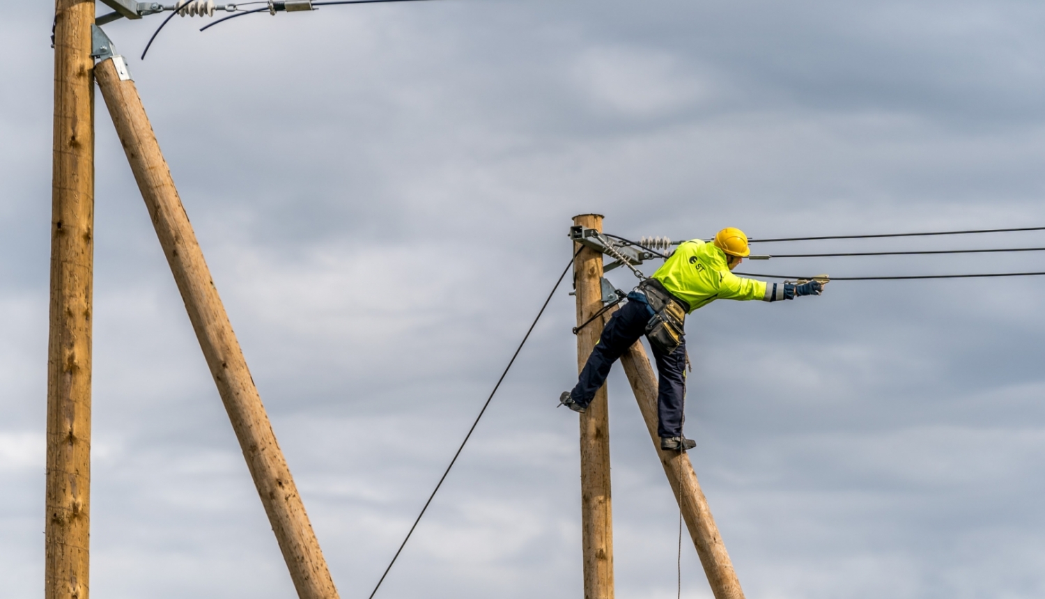 fotogrāfijā redzams elektriķis un elektrības stabi